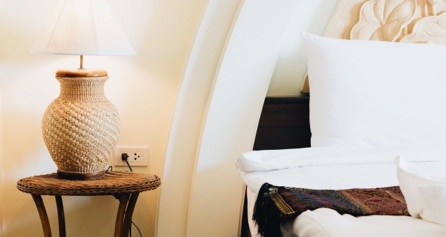 wicker lamp on table next to white bed